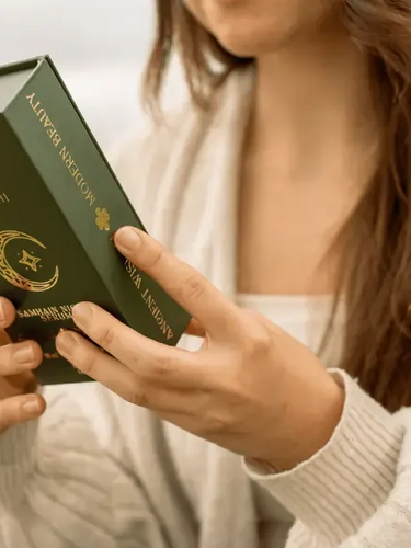 Woman holding green AINMHÍ skincare box with gold design, natural Irish beauty product