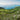 Lush green Irish coastline with rolling hills, stone walls, and distant islands under a clear sky